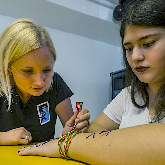 Sozialarbeiterin malt ein Henna-Tattoo auf die Hand einer Jugendlichen.