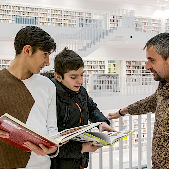 Sozialarbeiter trifft sich mit zwei Jugendlichen in der Stadtbibliothek.